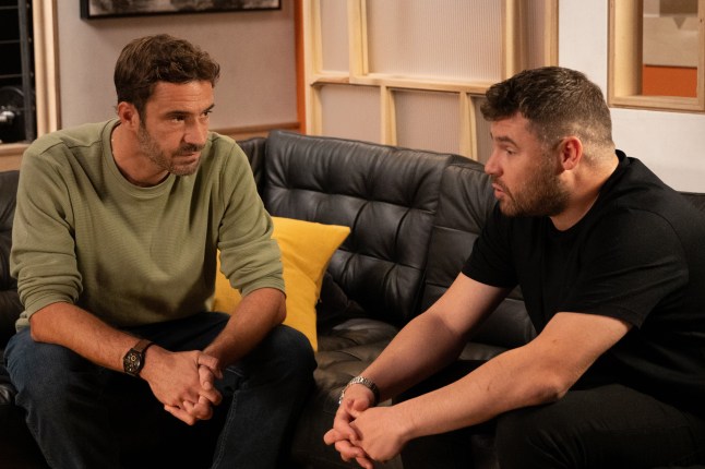 Aaron and John have a conversation on their sofa in Emmerdale