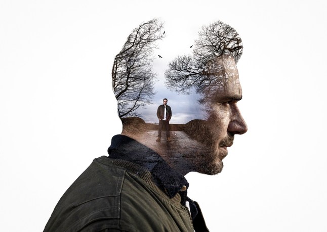 Profile shot of John Sugden on a white background with him standing on a road inside his head in an Emmerdale promo shot