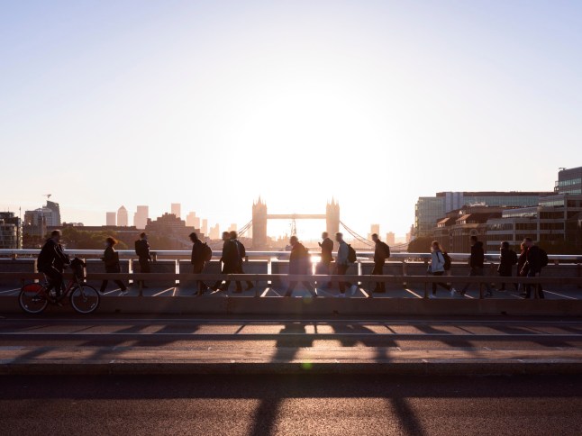 UK, London, crowd of business people walking to work with view of Tower Bridge and Canary Wharf behind