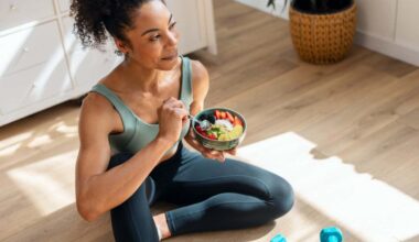 A woman eating a bowl of fruit while wearing exercise clothes