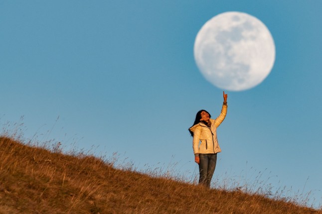 Mandatory Credit: Photo by Lorenzo Di Cola/NurPhoto/Shutterstock (15249706g) A woman "touching" with a finger "Pink" full Moon is seen in the municipality of Calascio, Italy, on April 11th, 2025. Some Eastern Native American tribes used to call April's full moon the "pink moon" due to its connection with early spring wildflowers. April full moon is also a supermoon, which occurs when the moon reaches its closest point to Earth in its orbit, making it appear larger and more radiant than usual. Pink Full Moon Over Abruzzo, Italy, Calascio - 11 Apr 2025