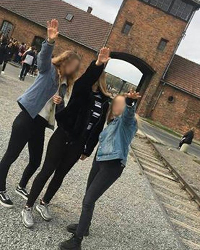 Three teenagers raising their hands in a Nazi salute at Auschwitz.