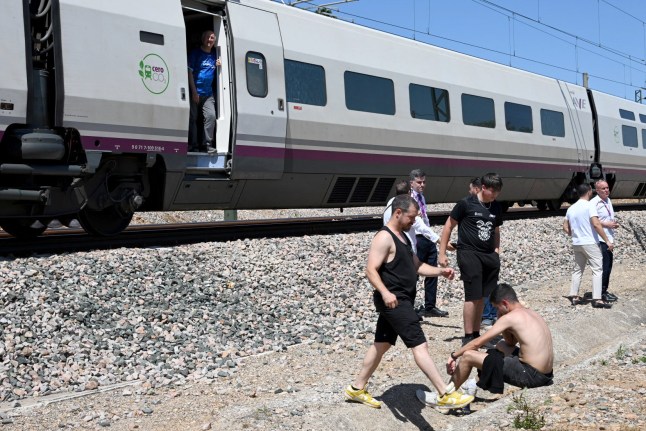 Passengers stand next to a stopped RENFE high-speed AVE train near Cordoba on April 28, 2025, during a massive power cut affecting the entire Iberian peninsula and the south of France. A 