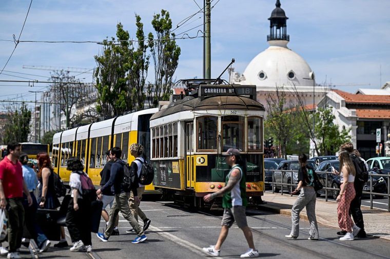 Pedestrians walk past a stopped waggon tram in a street of downtown Lisbon on April 28, 2025, during a massive power cut affecting the entire Iberian peninsula and the south of France. A 