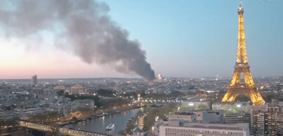 Large plume of smoke over Paris with the Eiffel Tower in the background.