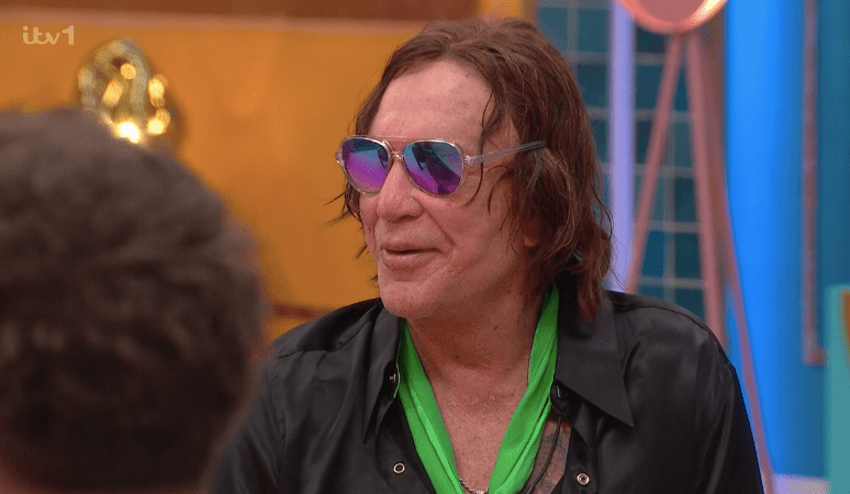 Screenshot of a man wearing sunglasses and a green scarf.