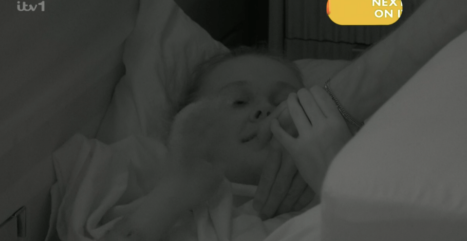Screenshot of a person holding a child's hand in bed.