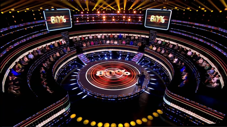 Game show set with audience and 80% displayed on screens.