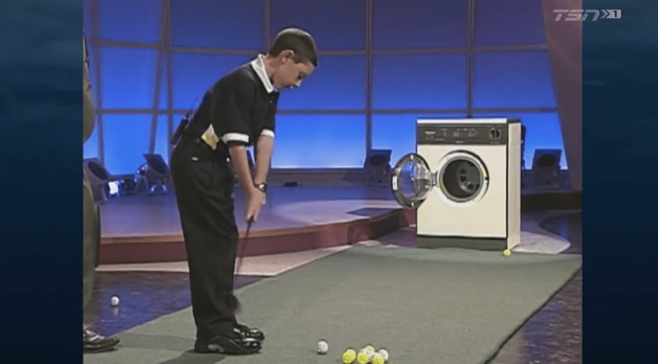 Screenshot of a young boy putting a golf ball toward a washing machine.