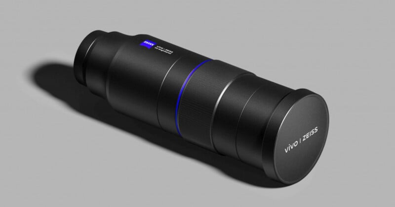 A black, cylindrical camera lens with the label "Vivo ZEISS" is positioned diagonally on a gray background. The lens features sleek grooves and a subtle blue ring near the center.