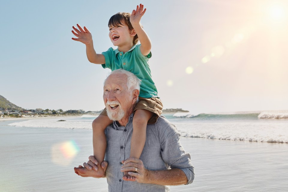 Grandfather carrying grandson on his shoulders at the beach.