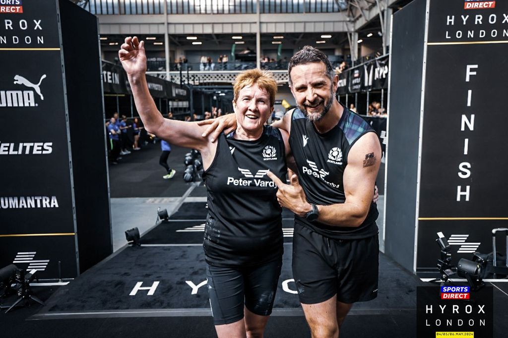 woman in black workout gear at Hyrox celebrating her win 