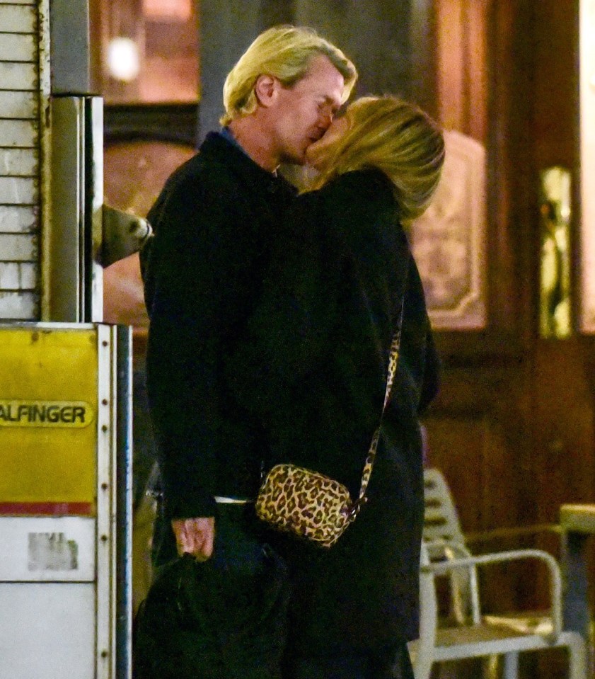 Couple kissing on a street at night.