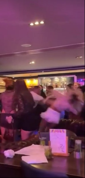 Woman being shoved by two men in a bar.