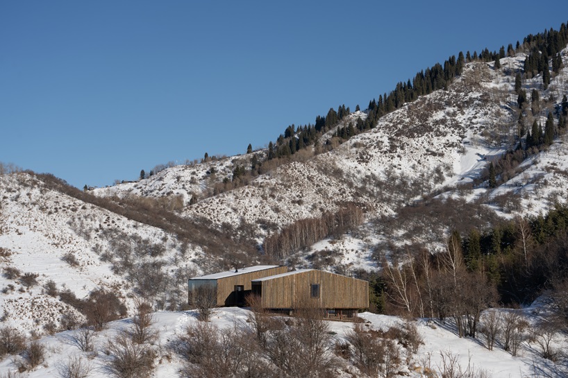 reclaimed dark larchwood clads aum cabins' facades amid mountainscape in kazakhstan