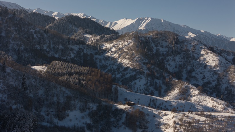 reclaimed dark larchwood clads aum cabins' facades amid mountainscape in kazakhstan