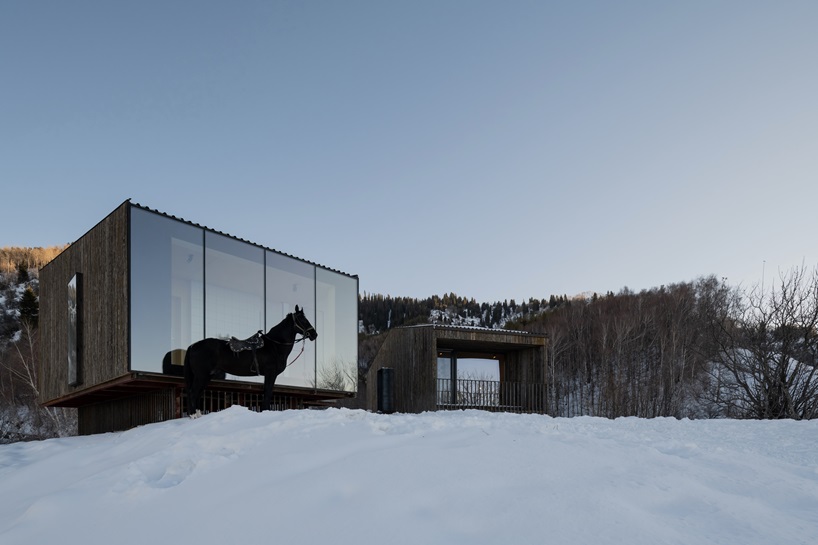 reclaimed dark larchwood clads aum cabins' facades amid mountainscape in kazakhstan