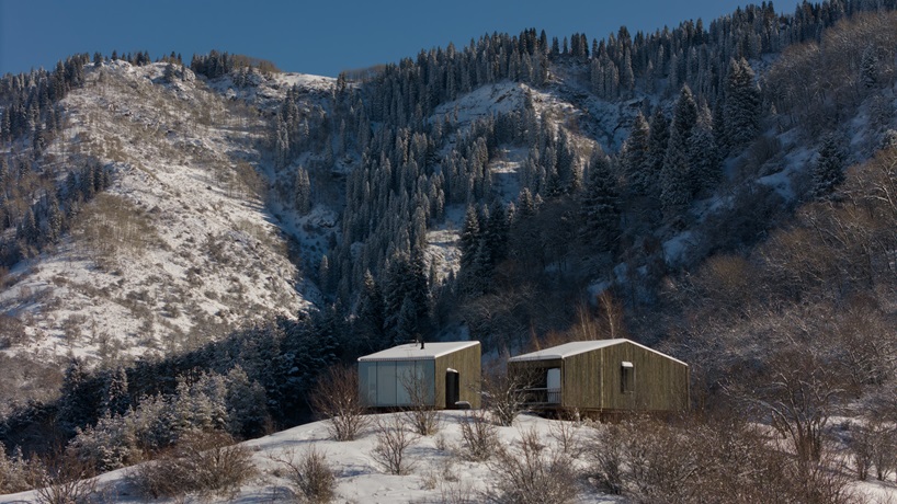 reclaimed dark larchwood clads aum cabins' facades amid mountainscape in kazakhstan