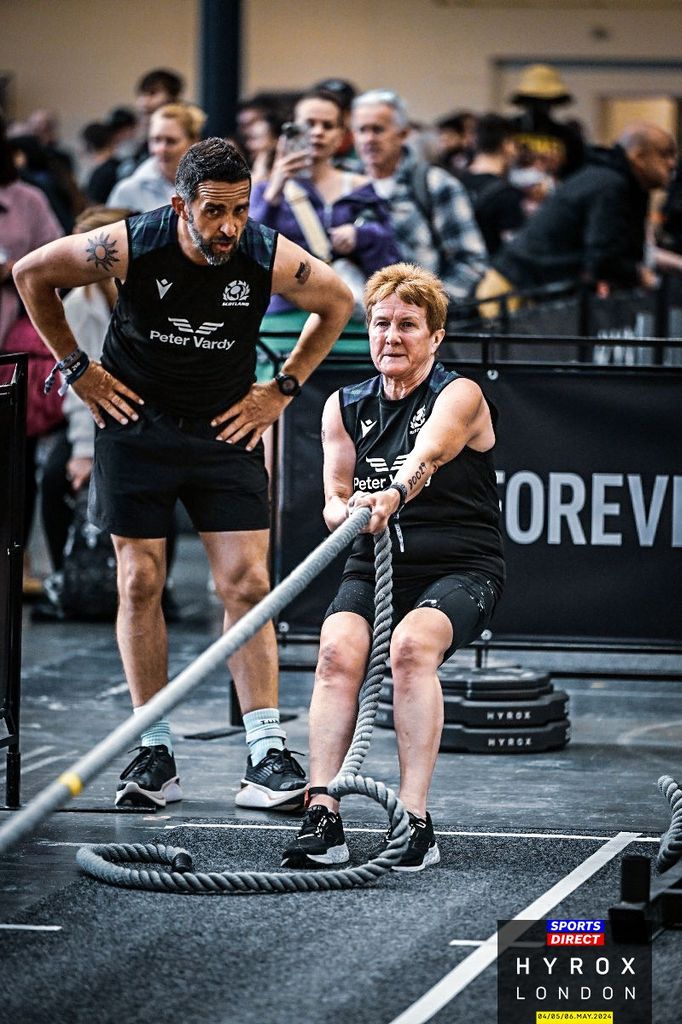 Older woman pulling on a big rope at the hyrox fitness competition