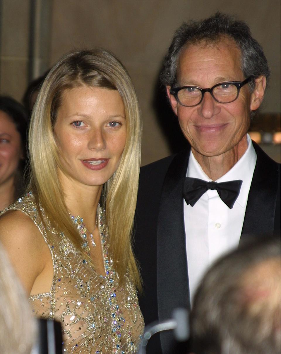 Woman in a glittering dress and man in a tuxedo at an event, smiling at the camera