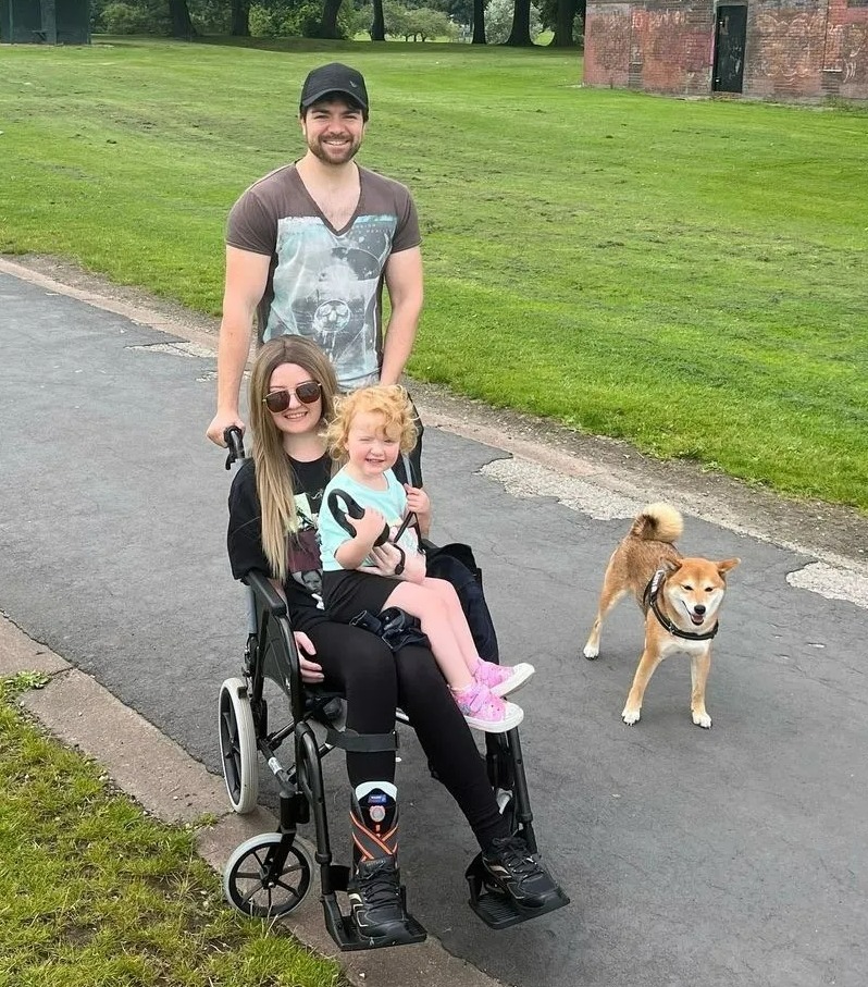Family with young child and dog in a park; woman in wheelchair.