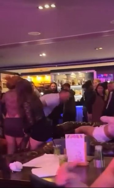 A woman being shoved by two men in a bar.