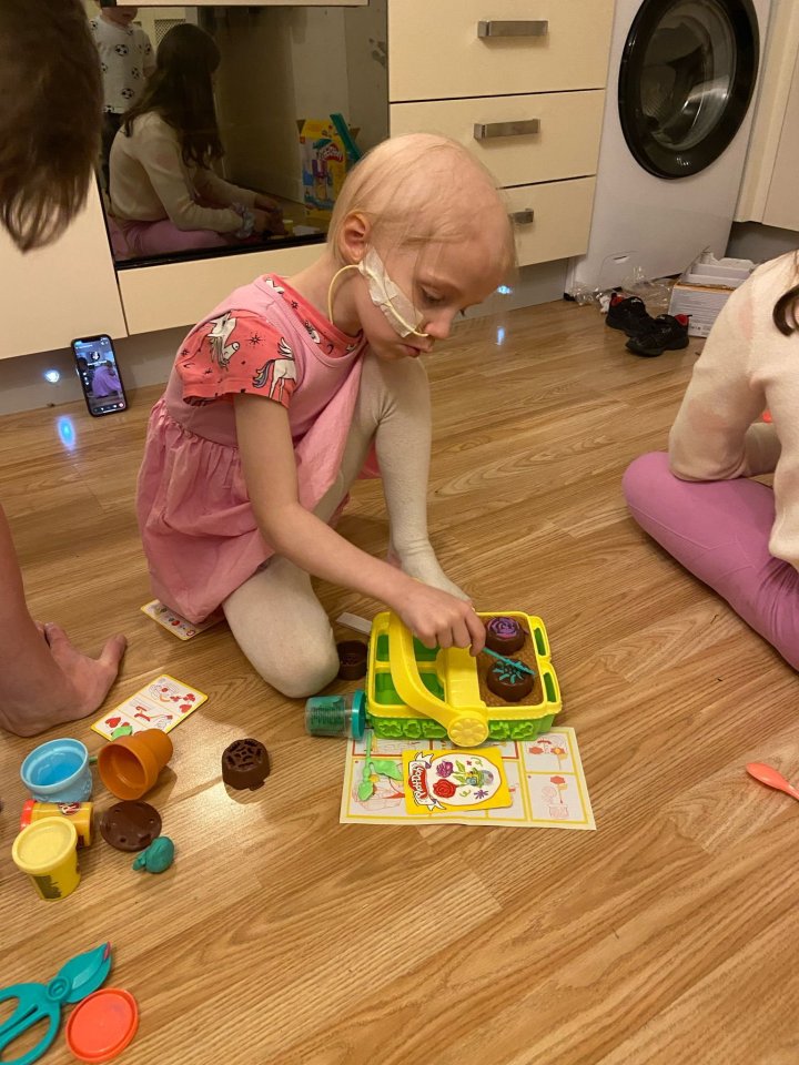 A young girl with a nasal cannula plays with playdough.