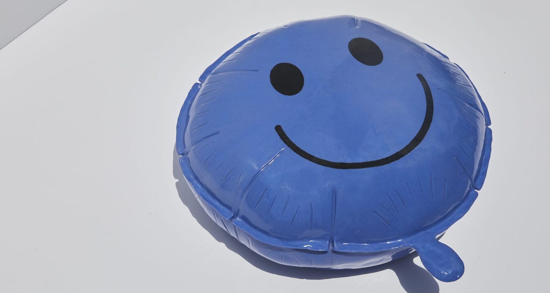 a ceramic sculpture of a blue happy face balloon