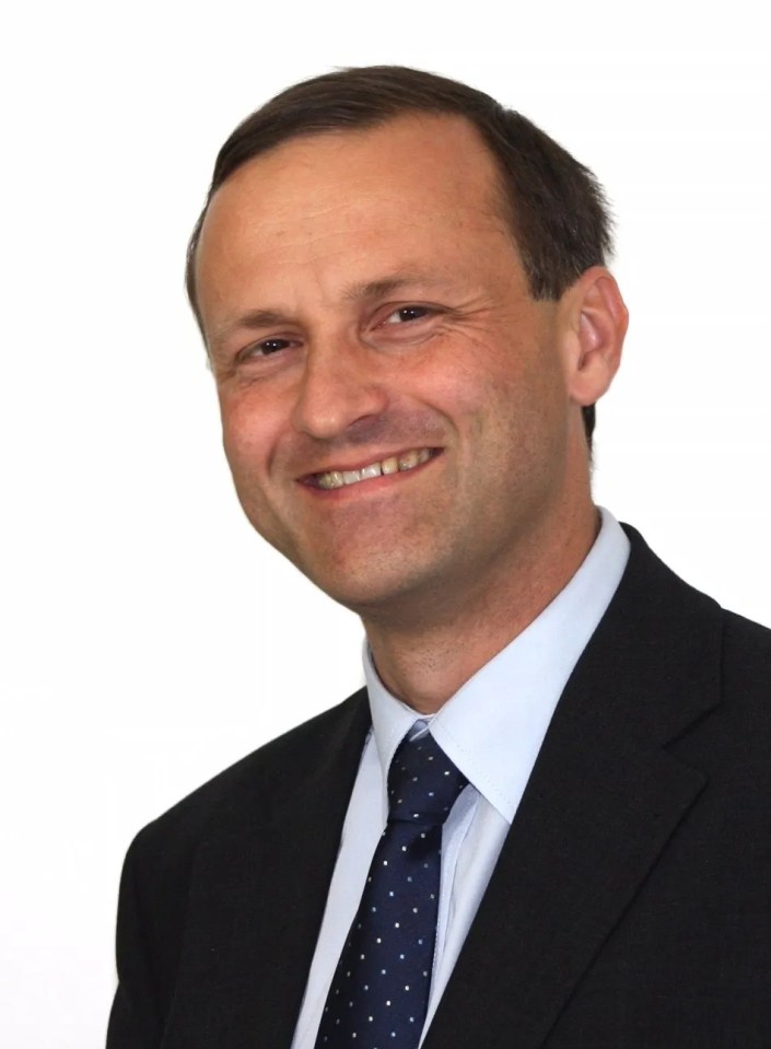 a man in a suit and tie smiles for the camera