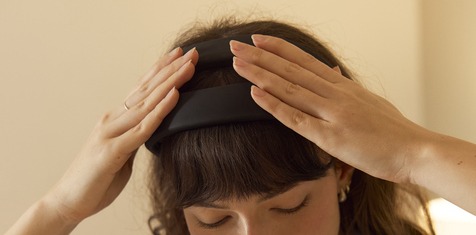 Woman putting on a headband to alleviate period pain.