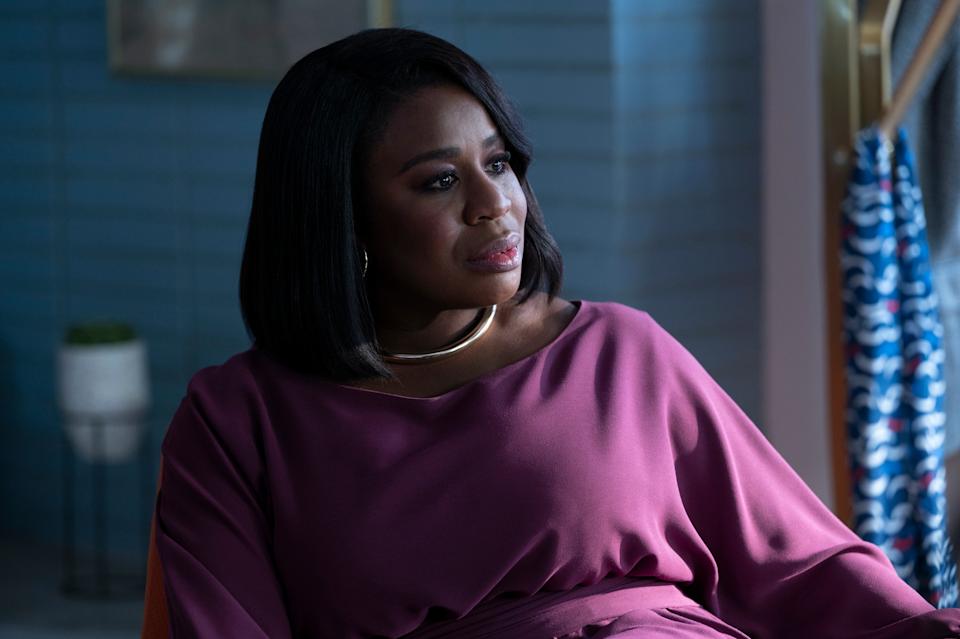 Woman in a stylish, long-sleeved top sits thoughtfully in a modern setting