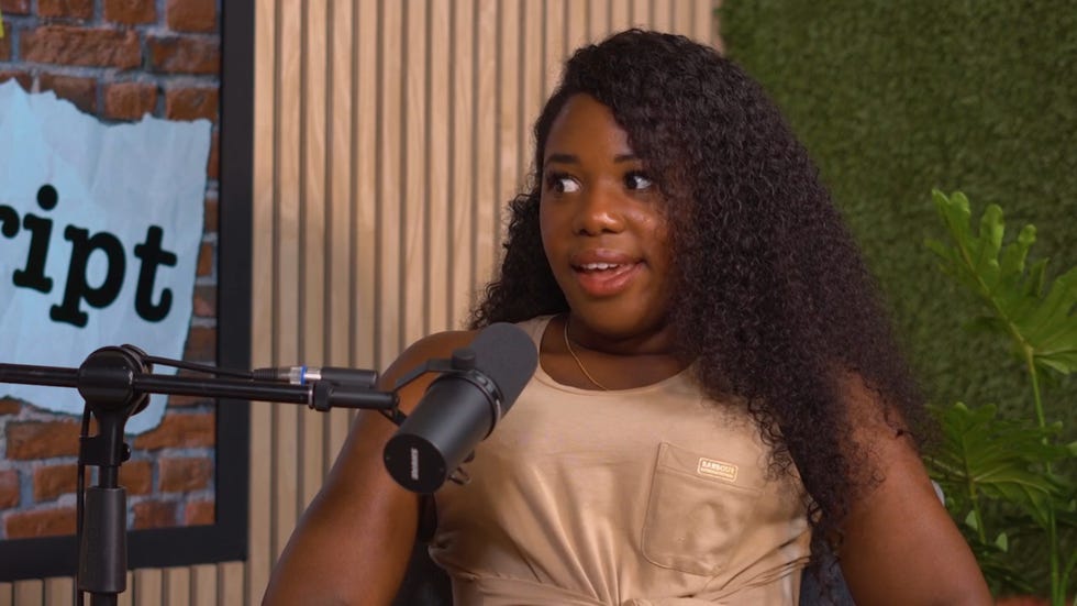 channique sterling brown speaking into a microphone on the off script podcast, wearing an off cream coloured dress