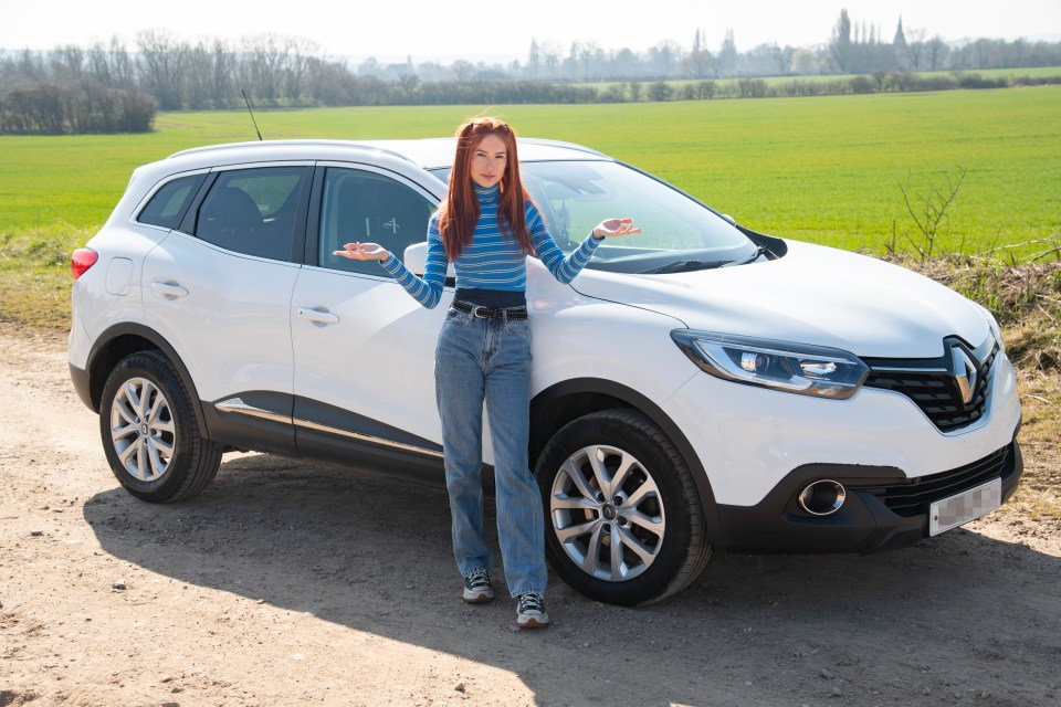 A woman stands next to her white SUV.