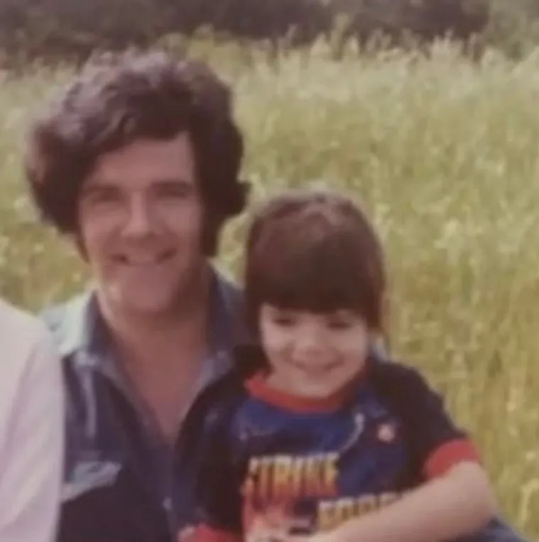 Photo of a man and a young child in a field.