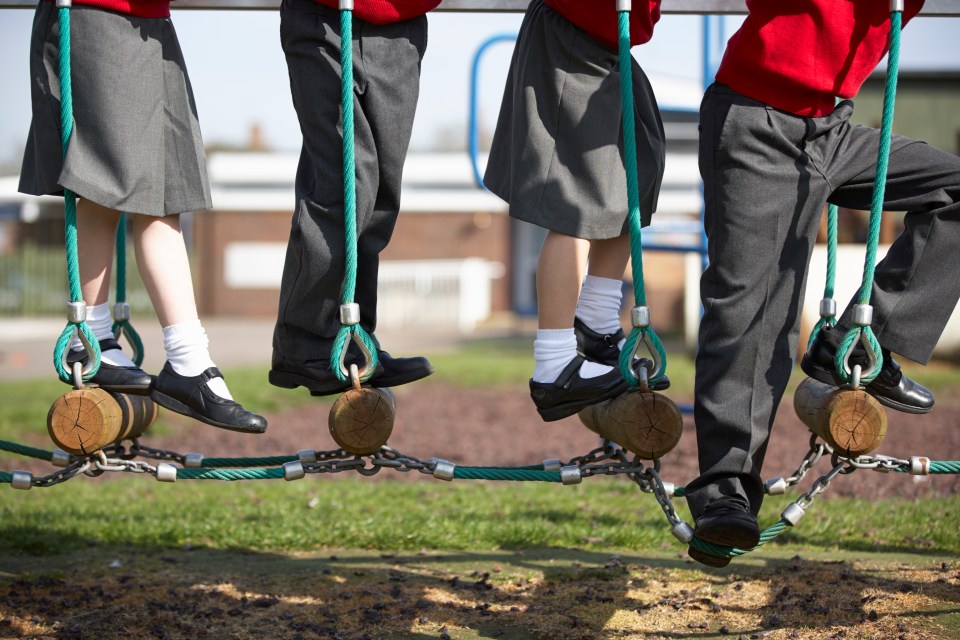 Elementary school children in uniform walking a balance beam.
