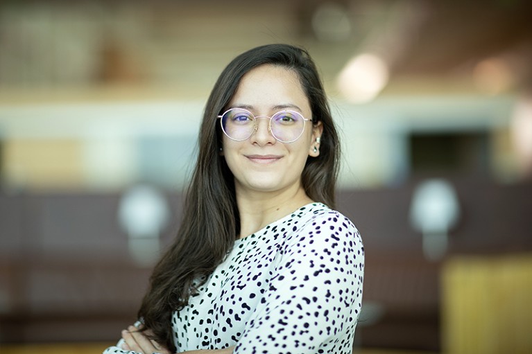 A woman wearing glasses, in and black and white spotty top, looks directly at the camera