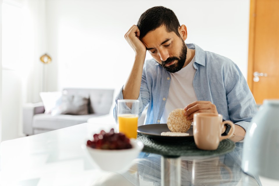 Depressed man with a small appetite eating breakfast.