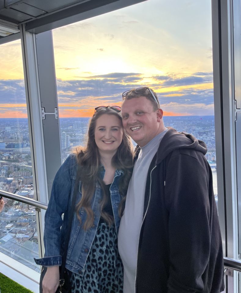 Couple posing for a photo at sunset, overlooking a city.