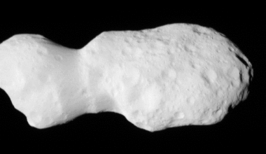 Gif of Asteroid Donaldjohanson, as seen by the Lucy spacecraft during its close flyby. The asteroid looks like two lobes, attached by a thinner cylinder, like a barbell with very large weights. One lobe is smaller than the other. Although they are both about the same circumference, the smaller lobe is less wide than the other. The asteroid is a smooth, light gray surface, with smooth-edged craters dimpling its surface. The larger lobe has many more craters. The asteroid moves closer to the camera, pushing in on the larger lobe. Then it rotates slightly to look along the asteroid long-ways.