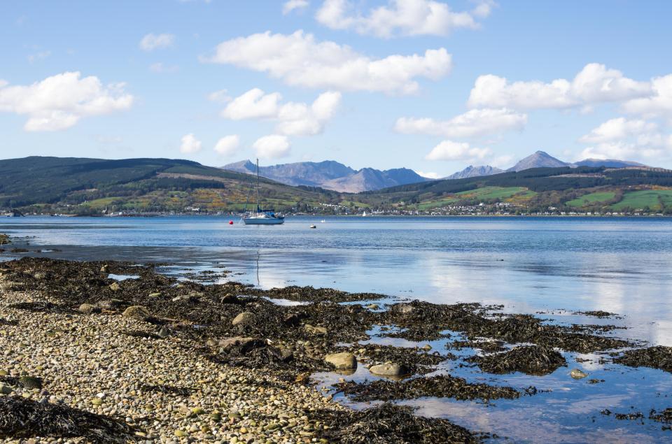 Lamlash Bay, Isle of Arran, Scotland: sailboat in calm waters with mountains in the background.