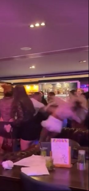 A woman being shoved by two men in a bar.
