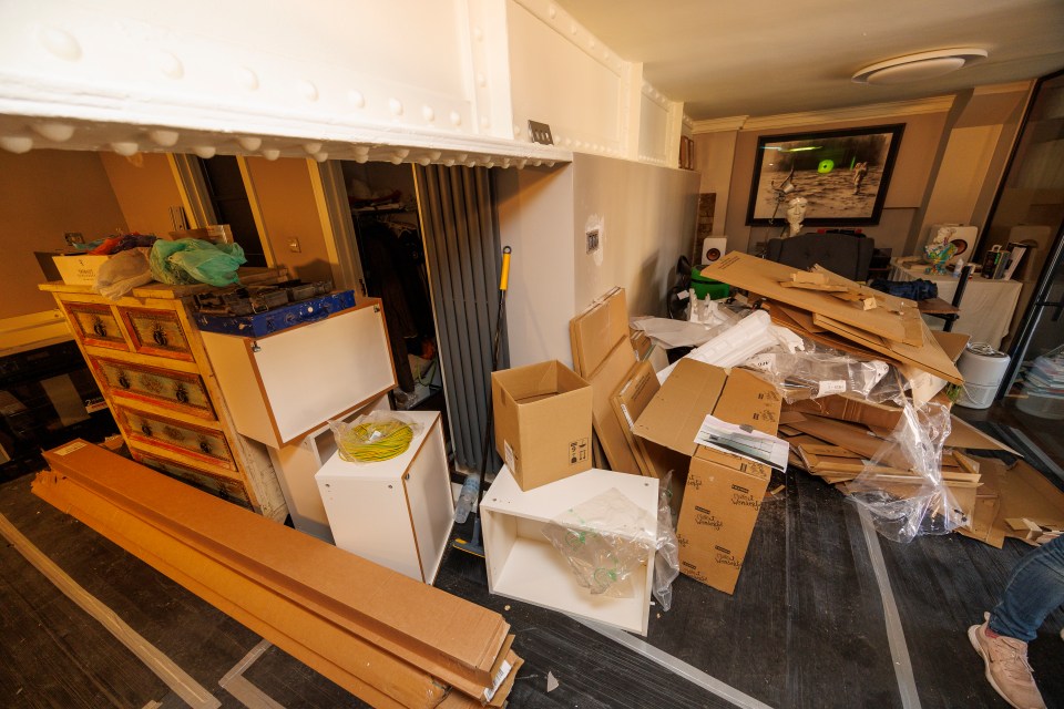 Messy room with unpacked boxes and building materials.