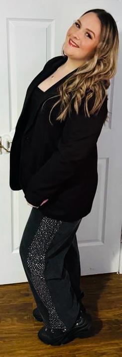 Woman in black blazer and rhinestone pants.