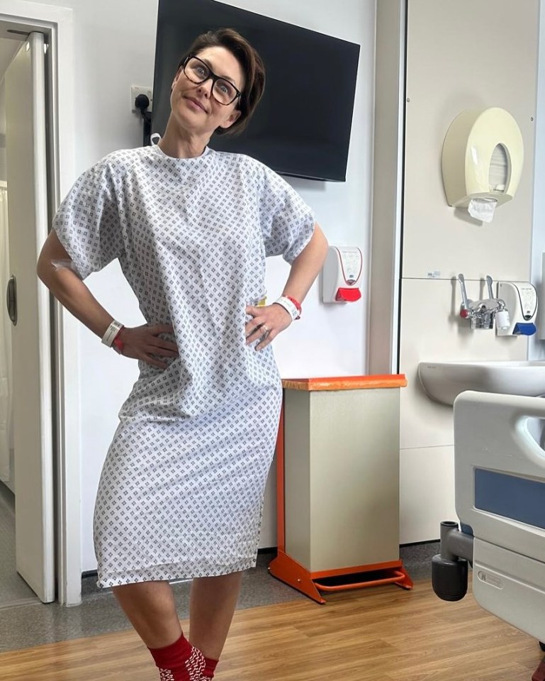 Woman in a hospital gown and red socks poses in a hospital room.