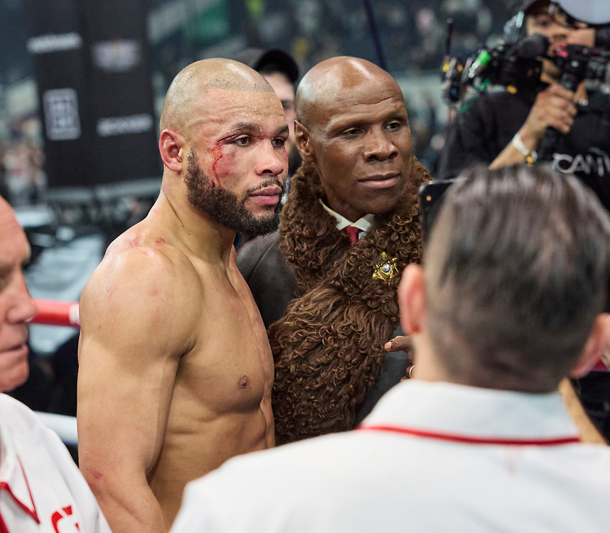 A boxer with cuts on his face and shoulders stands next to a man in a fur stole.