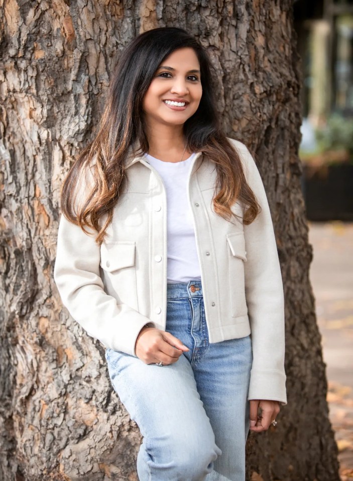 Portrait of a smiling woman leaning against a tree.