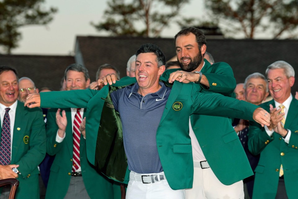 Scottie Scheffler placing the green jacket on Rory McIlroy at the Masters Tournament.