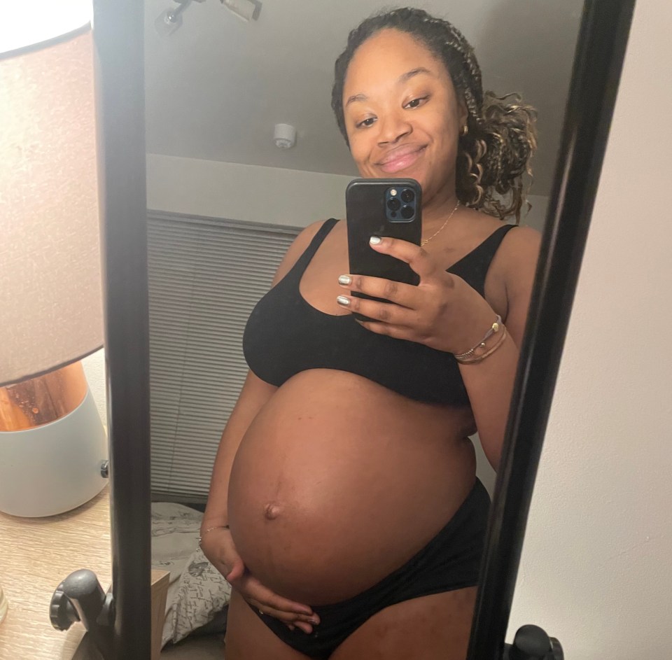 A pregnant woman taking a selfie in a mirror.