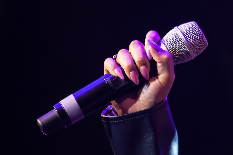 Woman's hand holding a wireless microphone.