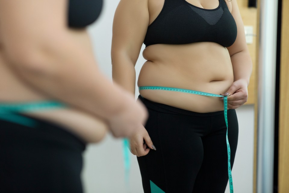 Woman measuring her waist with a tape measure.
